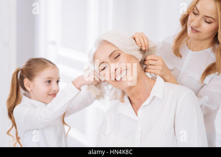 Positivo donna invecchiato in appoggio a casa con i membri della sua famiglia Foto Stock