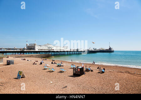 Brighton, Sussex, Regno Unito - 16 Maggio 2014: turisti rilassante sulla spiaggia accanto al molo di Brighton dal 1899. Brighton è il più grande e più Foto Stock