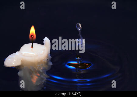 Candela di illuminazione sul buio gli spruzzi di acqua la superficie Foto Stock