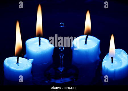 Alcuni accendendo candele on dark gli spruzzi di acqua la superficie Foto Stock