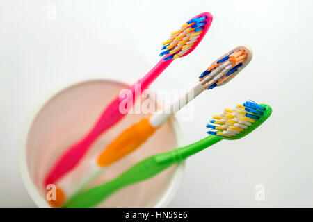 Immagine ravvicinata di set di spazzolini da denti multicolore in vetro su pulire il wc su sfondo bianco, concetto dentale. Foto Stock