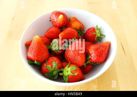 Le fragole in bianco ciotola sul tavolo di legno Foto Stock