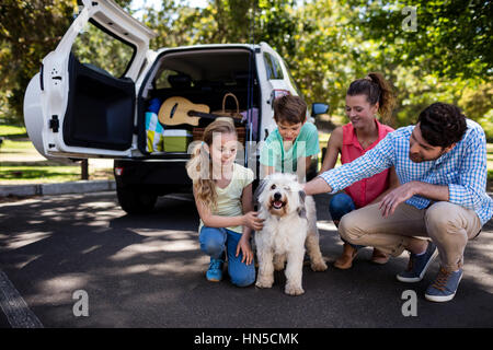 La famiglia felice seduta nel parco con il loro cane Foto Stock