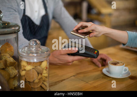 La donna il pagamento fattura tramite lo smartphone utilizzando la tecnologia NFC in cafe