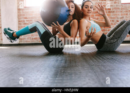 Due donne sportivo formazione con palla medica in palestra. Ragazze che lavorano fuori per modellare il loro corpo. Foto Stock