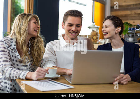 Happy amici interagendo durante l'utilizzo di laptop in cafÃƒÂ© Foto Stock