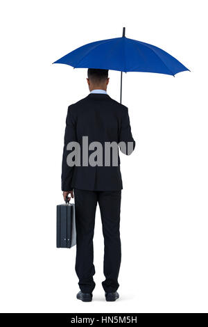Vista posteriore del businessman holding ombrello blu e una valigetta contro uno sfondo bianco Foto Stock