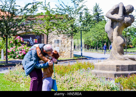 Giovane mimicing kissing statua nel giardino di rose a Praga Foto Stock
