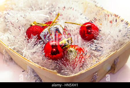 Anno nuovo Natale . Giocattoli in un cestello, rosso sfere, pigne, dolci caramelle di un giocattolo. Effetto di festa. Foto Stock