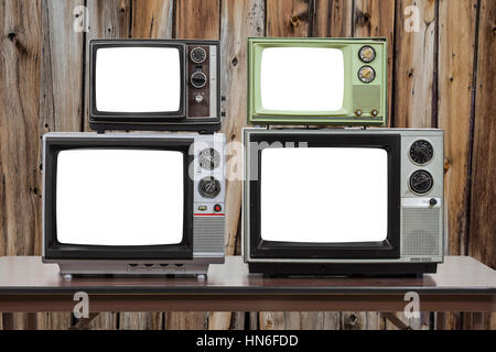 Quattro televisori vintage con tagliare fuori gli schermi e il legno vecchio muro. Foto Stock