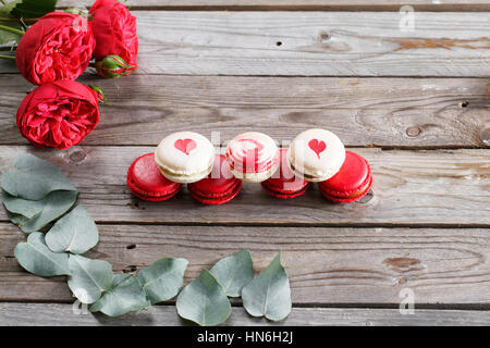 Amaretti al rosso e i dolci e le rose su sfondo di legno. dessert per la prima colazione il giorno di San Valentino. spazio copia Foto Stock