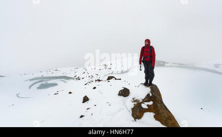 Escursionista permanente sulla roccia, congelati laghi smeraldo, Tongariro Alpine Crossing con la neve, il Parco nazionale di Tongariro, Southland Foto Stock