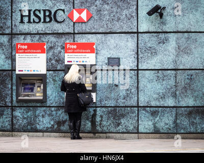 HSBC Bancomat Londra - una donna usa una sede HSBC le macchine di contanti nel centro di Londra con le telecamere di sicurezza monitoraggio dell'ATM. Foto Stock