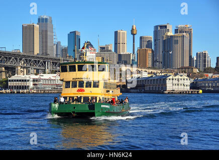 Uno di Sydney il famoso giallo e verde barche traghetto attraversa il porto di Darling Harbour a McMahons Point. In fondo è il Harbour Bridg Foto Stock