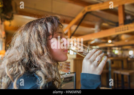 Giovane donna ragazza con degustazione e luce pallido birra dal vetro in legno rustico bar bavarese Foto Stock