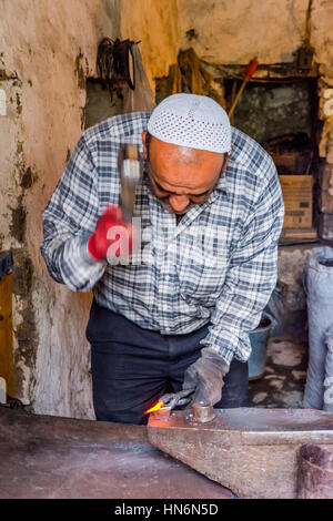 LAHICH, AZERBAIGIAN - 1 ottobre: Senior fabbro rendendo i chiodi con il martello e pinze in Lahich, famoso di smith tradizione. Ottobre 2016 Foto Stock