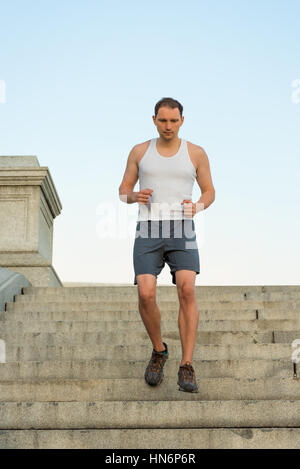 Montare giovane uomo che corre verso il basso passi fuori durante gli allenamenti Foto Stock