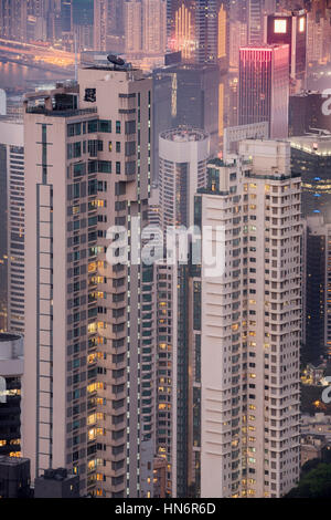 Vista ingrandita di un skyskraper in una popolosa città. Highrise edifici con blocchi di appartamenti di notte. Hong Kong, Cina Foto Stock