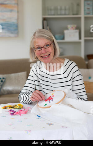 Senior donna facendo broidery a casa Foto Stock