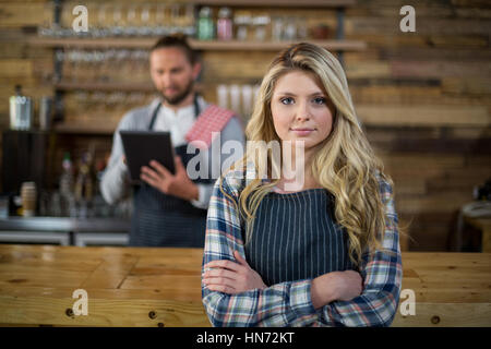 Ritratto di cameriera in piedi con le braccia incrociate al contatore in cafÃƒÂ© Foto Stock