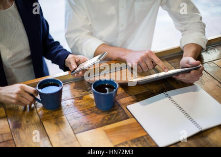 Sezione intermedia di imprenditori con tavoletta digitale al contatore in cafÃƒÂ© Foto Stock