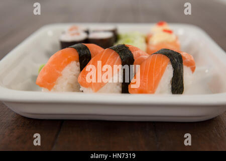 Tre nigiri sushi servita nella piastra bianca sul tavolo di legno Foto Stock