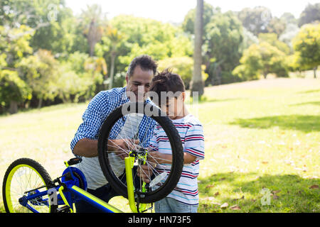 Il figlio e il padre a riparare le biciclette di parcheggiare in una giornata di sole Foto Stock