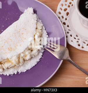 Casabe (ingaggiami, beiju, bob, biju) - flatbread di manioca (tapioca) con ricotta e miele e la tazza di caffè su sfondo di legno. Messa a fuoco selettiva Foto Stock