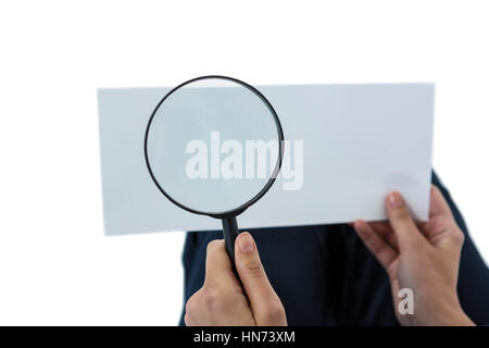 Close-up di donna tenendo la lente di ingrandimento su un foglio di carta contro uno sfondo bianco Foto Stock