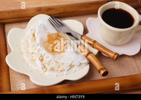 Casabe (ingaggiami, beiju, bob, biju) - flatbread di manioca (tapioca) con ricotta e miele e la tazza di caffè su sfondo di legno. Messa a fuoco selettiva Foto Stock