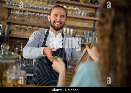 Cliente dando carta di credito alla cameriera durante la ricezione del pacco presso il contatore in cafÃƒÂ© Foto Stock