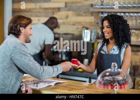 Sorridente cameriera serve una tazza di caffè al contatore in cafÃƒÂ© Foto Stock