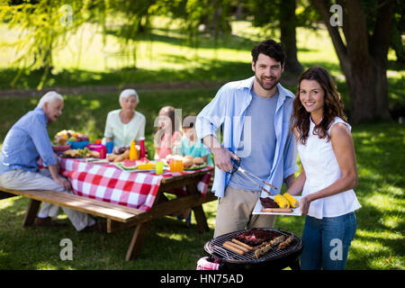 Ritratto di Coppia sorridente prepara barbecue nel parco Foto Stock