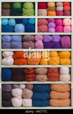 Coloratissime palle di lana su ripiani. Varietà di filati per maglieria. Diverse sfere di filato in diversi colori. Storage di filato. Foto Stock