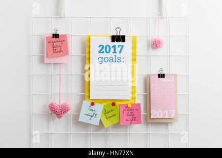 Risoluzioni del nuovo anno. Carta nota scritta con 2017 obiettivi sul diy maglia metallica a parete griglia organizzatore. Griglia metallica display con cuore rosa e pom pom. Foto Stock