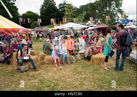 Le famiglie che si siedono su balle di fieno presso la bancarella del cibo e che si godono bere e mangiare al Port Eliot Festival Cornovaglia Foto Stock