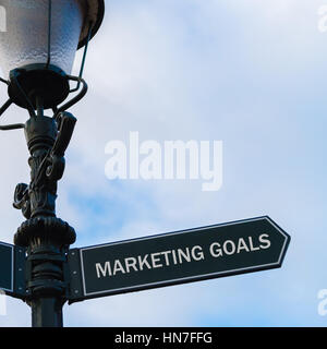 Illuminazione stradale pole con messaggio concettuale obiettivi di marketing sulla freccia direzionale blu su sfondo nuvoloso. Foto Stock