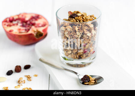 Fresh granola muesli in un bicchiere con mandorle e uvetta e melograno. Una sana prima colazione. Foto Stock