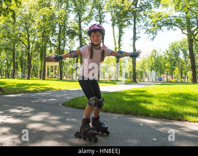 Bambina sui pattini a rotelle al summer park Foto Stock