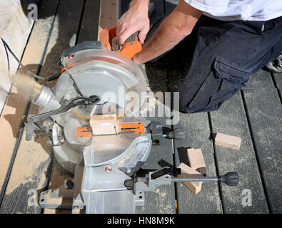Carpenter utilizzando una sega circolare per tagliare il bordo di legno Foto Stock
