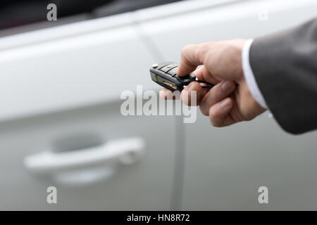 Imprenditore tenendo premuto un tasto auto con telecomando e premendo un pulsante, egli è di sbloccare la porta, canto close up Foto Stock