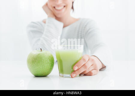 Giovane donna sorridente bere un sano e naturale di succo verde fatta con mele, dieta sana e concetto detox Foto Stock