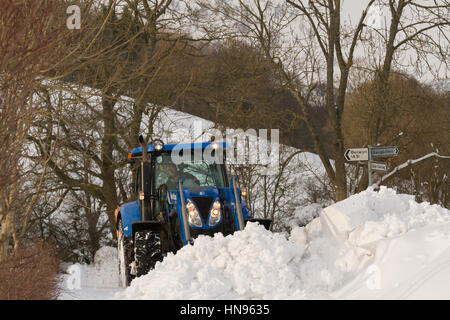 Il contadino si tenta di cancellare la neve profonda dopo una molto forti nevicate nelle zone rurali a Llangollen Galles del Nord Foto Stock