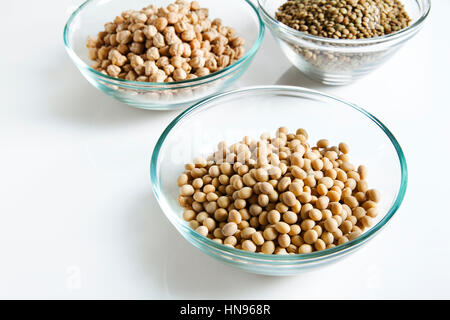 I fagioli di soia in un recipiente e altri legumi su bianco Foto Stock
