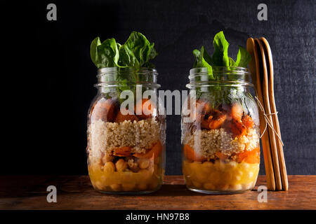 Vasetti di vetro con insalata calda: Ceci, arrots, quinoa, arrosto di zucca e spinaci. Pranzo sano Foto Stock
