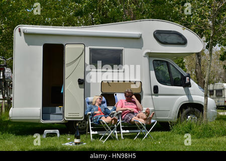 L uomo e la donna seduta sul campeggio sedie per la loro casa a motore e godersi la loro libertà in vacanza Foto Stock