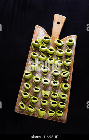 Ravioli . verde tortellini italiano con spinaci e ricotta in una piastra con salsa di pomodoro e formaggio parmigiano. Un sano comfort food Foto Stock