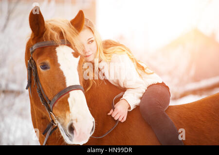 Pilota giovane ragazza con i capelli lunghi che giace sul collo del cavallo. Sfondo di amicizia Foto Stock