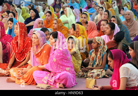 Le donne sedute a terra ad un matrimonio Sikh in Malesia indossando abiti tradizionali molto colorati. Foto Stock