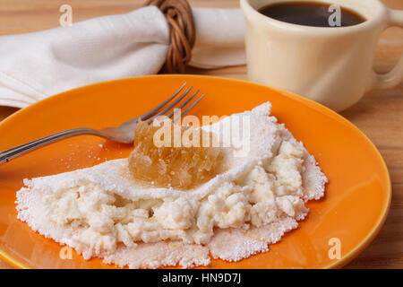 Casabe (ingaggiami, beiju, bob, biju) - flatbread di manioca (tapioca) con ricotta e miele e la tazza di caffè su sfondo di legno. Messa a fuoco selettiva Foto Stock